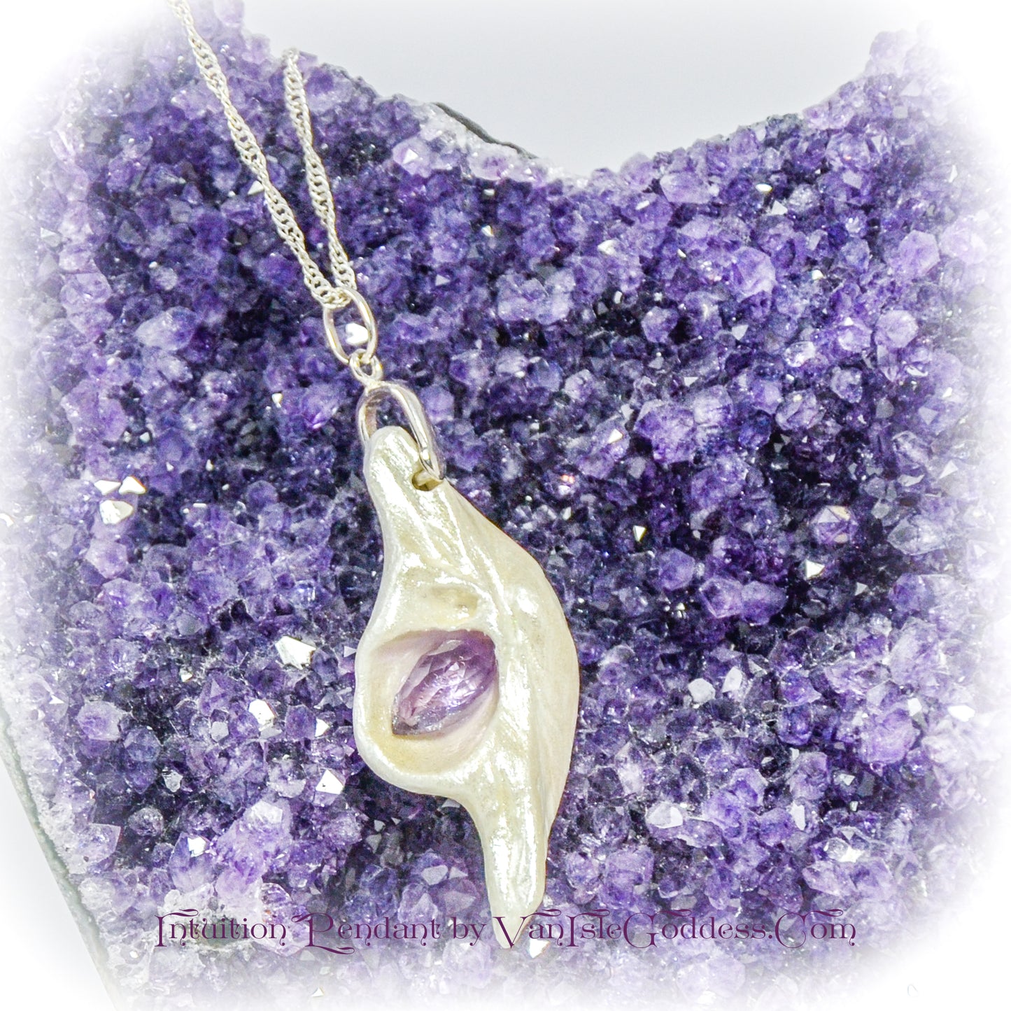 Intuition a natural seashell pendant with a beautiful rose cut marquise Amethyst.  The pendant is resting on a cluster of amethysts.