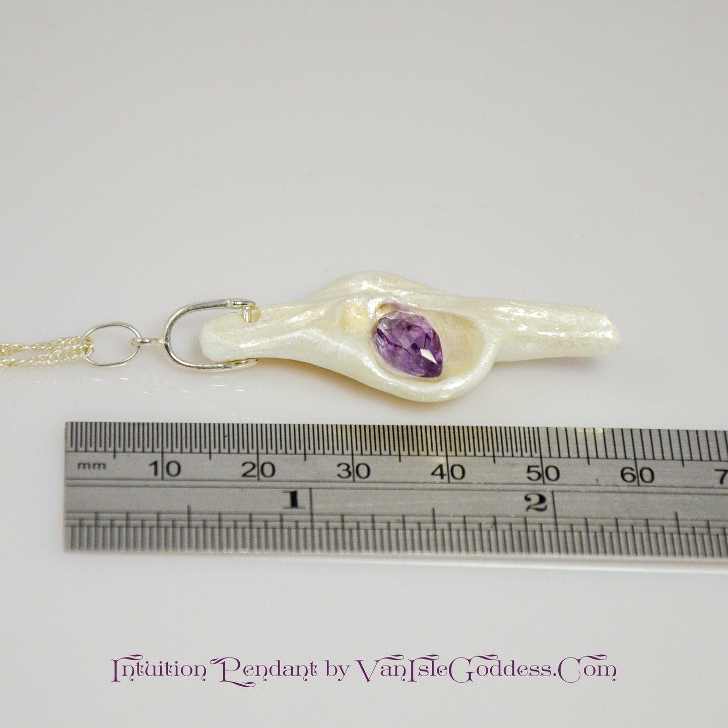 Intuition a natural seashell pendant with a beautiful rose cut marquise Amethyst.  The pendant is shown along side a ruler so the viewer can see the length of the pendant.