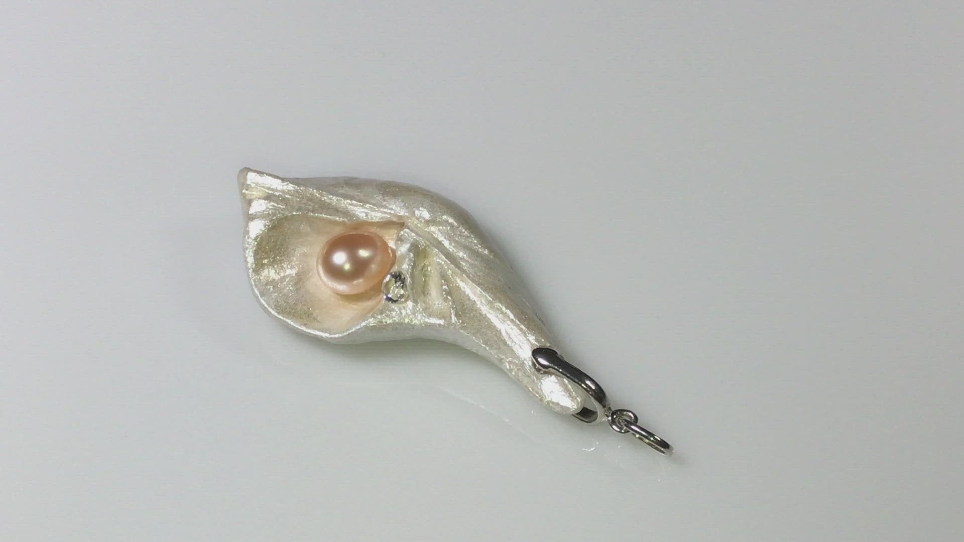 Athena is the name of the pendant being showcased.  It is a natural seashell from the beaches of Vancouver Island. The pendant has a real pink freshwater pearl and a faceted herkimer diamond. It is being showcased in the video.