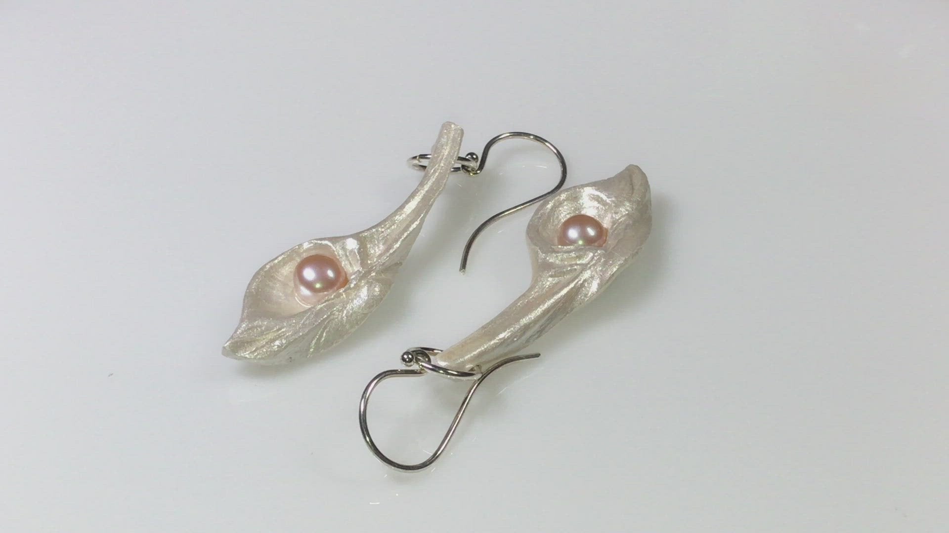 A video showcasing Sea Plume natural seashell earrings with real pink freshwater pearls.